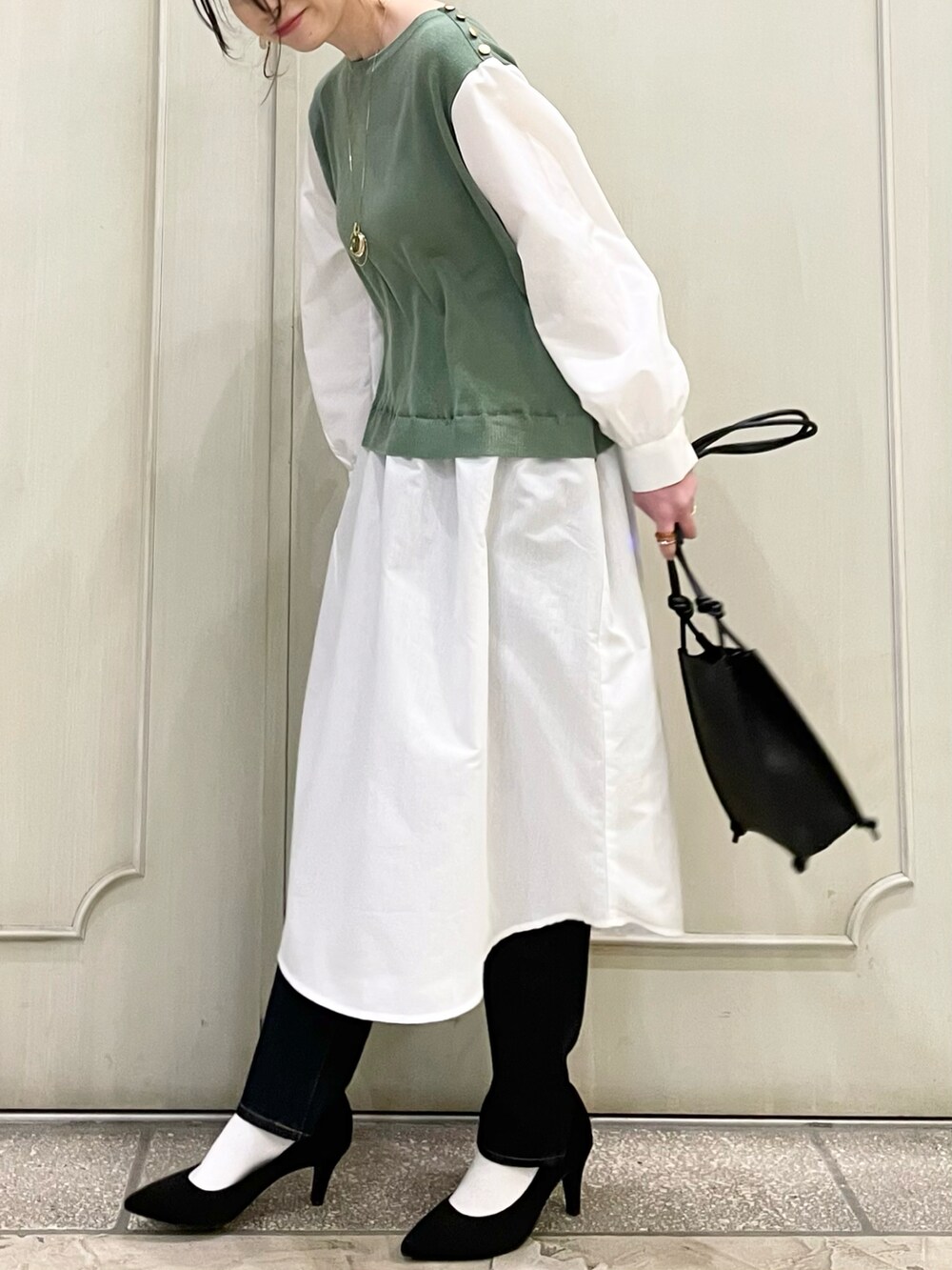 グリーン系のワンピース、ブラック系のショルダーバッグ、ブルー系のデニムパンツを着用したレディースの春コーディネートの3枚目の写真