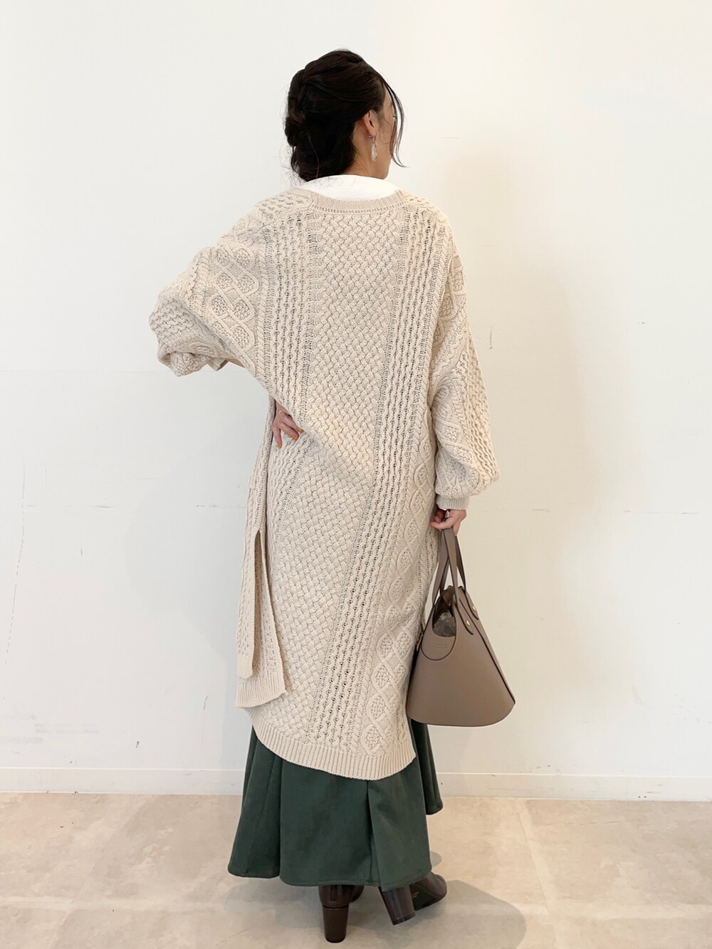 グリーン系のワンピース、ベージュ系のカーディガン/ボレロ、ホワイト系のTシャツ/カットソーを着用したレディースの秋コーディネートの3枚目の写真
