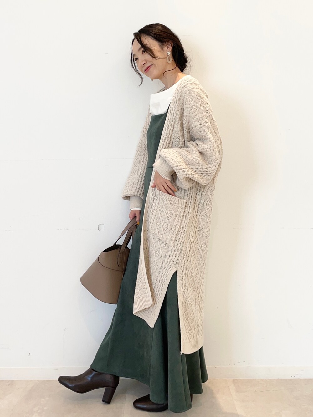 グリーン系のワンピース、ベージュ系のカーディガン/ボレロ、ホワイト系のTシャツ/カットソーを着用したレディースの秋コーディネートの2枚目の写真