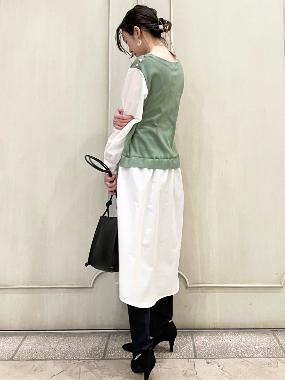 グリーン系のワンピース、ブラック系のショルダーバッグ、ブルー系のデニムパンツを着用したレディースの春コーディネートの2枚目の写真