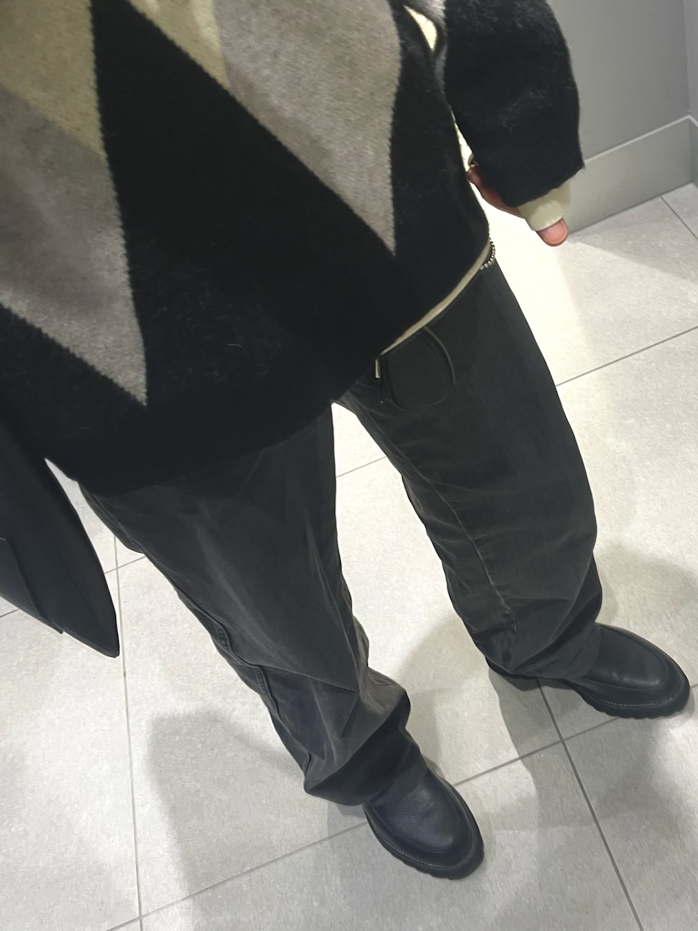 ブラック系のパンツ、ブラック系のドレスシューズ、ホワイト系のニット/セーターを着用したメンズの冬コーディネートの3枚目の写真