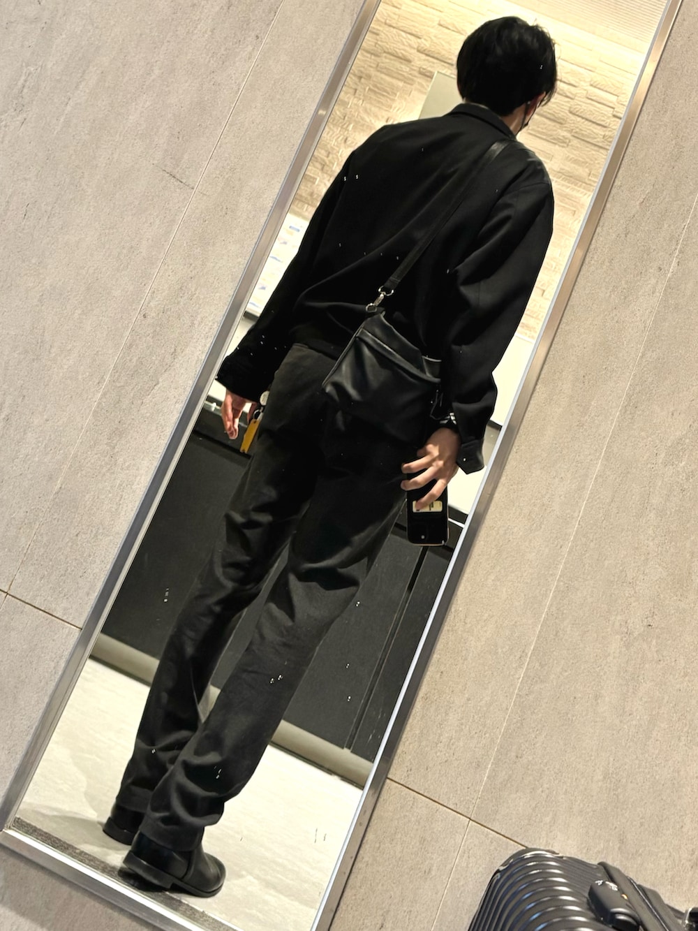 グレー系のスラックス、その他のビジネスシャツ、ブラック系のブルゾンを着用したメンズの春コーディネートの2枚目の写真