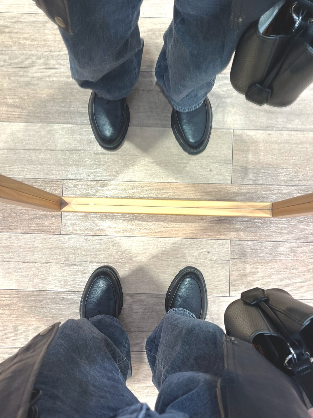グレー系のデニムパンツ、ブラック系のニット/セーター、ブラック系のドレスシューズを着用したメンズの冬コーディネートの5枚目の写真