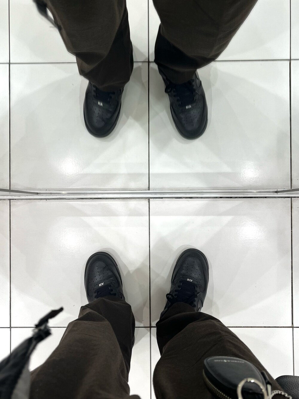 ブラウン系のパンツ、ブラック系のスニーカー、ブラック系のショルダーバッグを着用したメンズの冬コーディネートの5枚目の写真