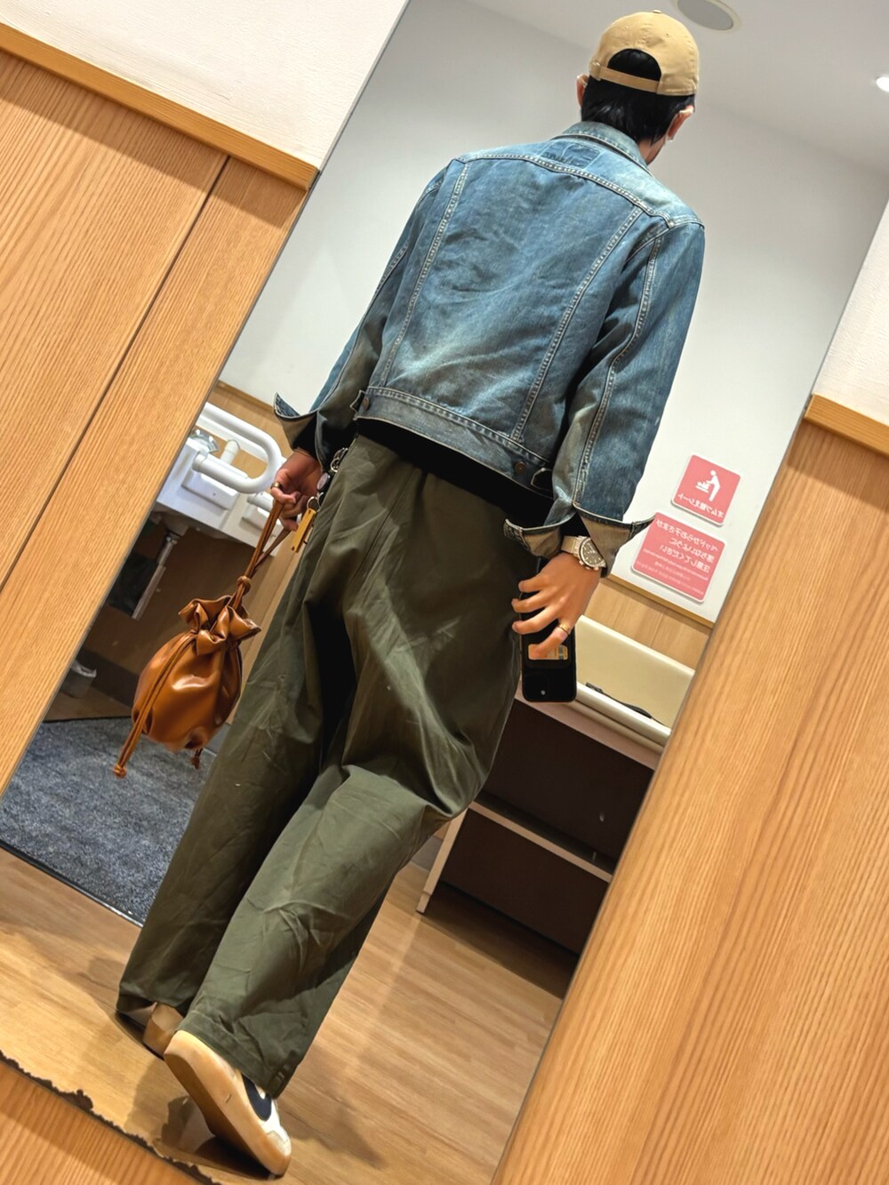 ホワイト系のスニーカー、ブラック系のニット/セーター、ブルー系のデニムジャケットを着用したメンズの秋コーディネートの2枚目の写真