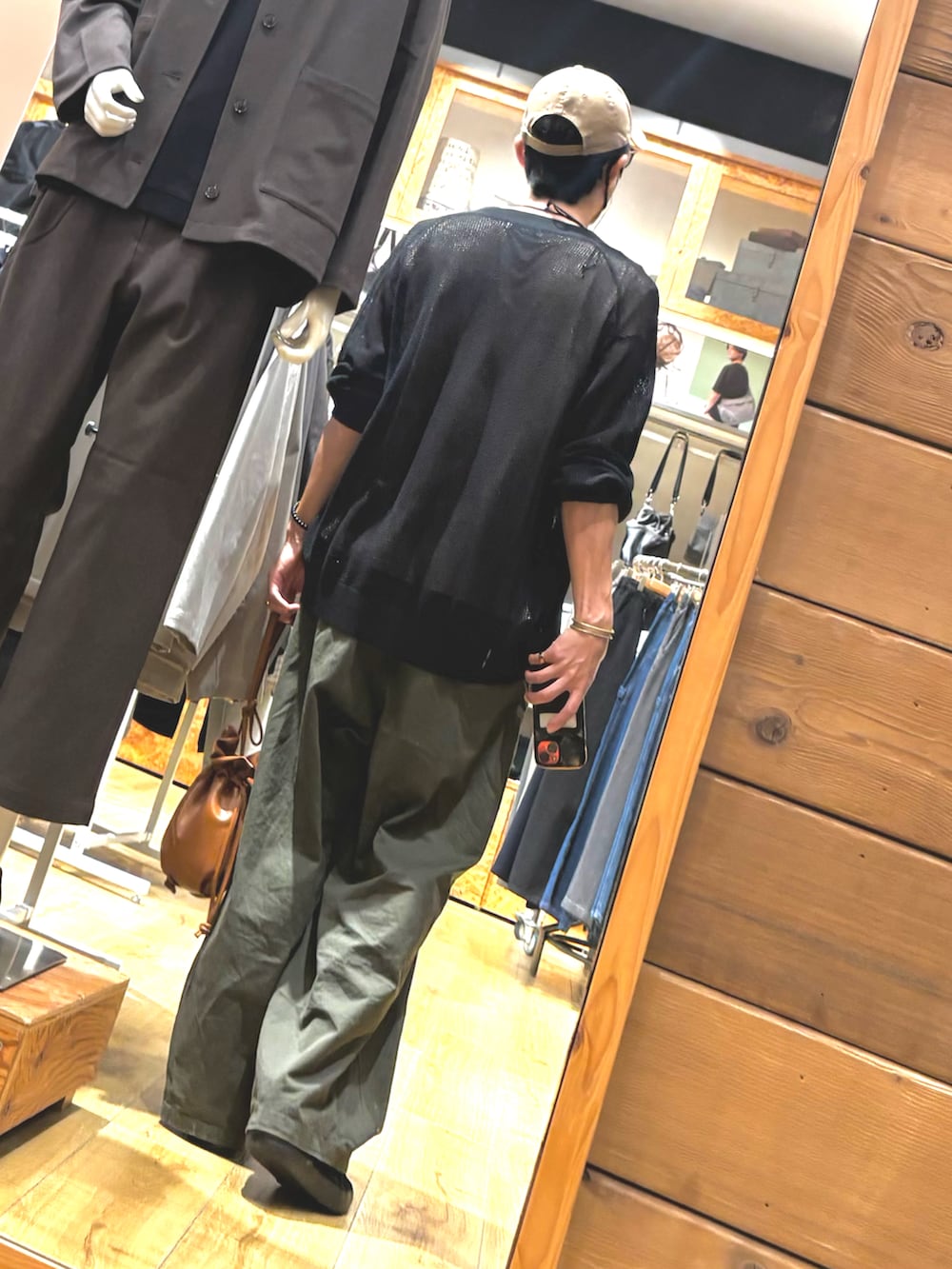 ブラウン系のショルダーバッグ、ブラック系のスニーカー、ベージュ系のタンクトップを着用したメンズの秋コーディネートの2枚目の写真