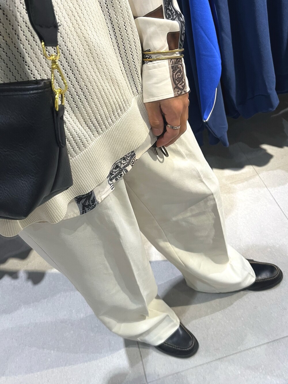 ブラック系のローファー、ホワイト系のスラックス、ベージュ系のベストを着用したメンズの秋コーディネートの3枚目の写真