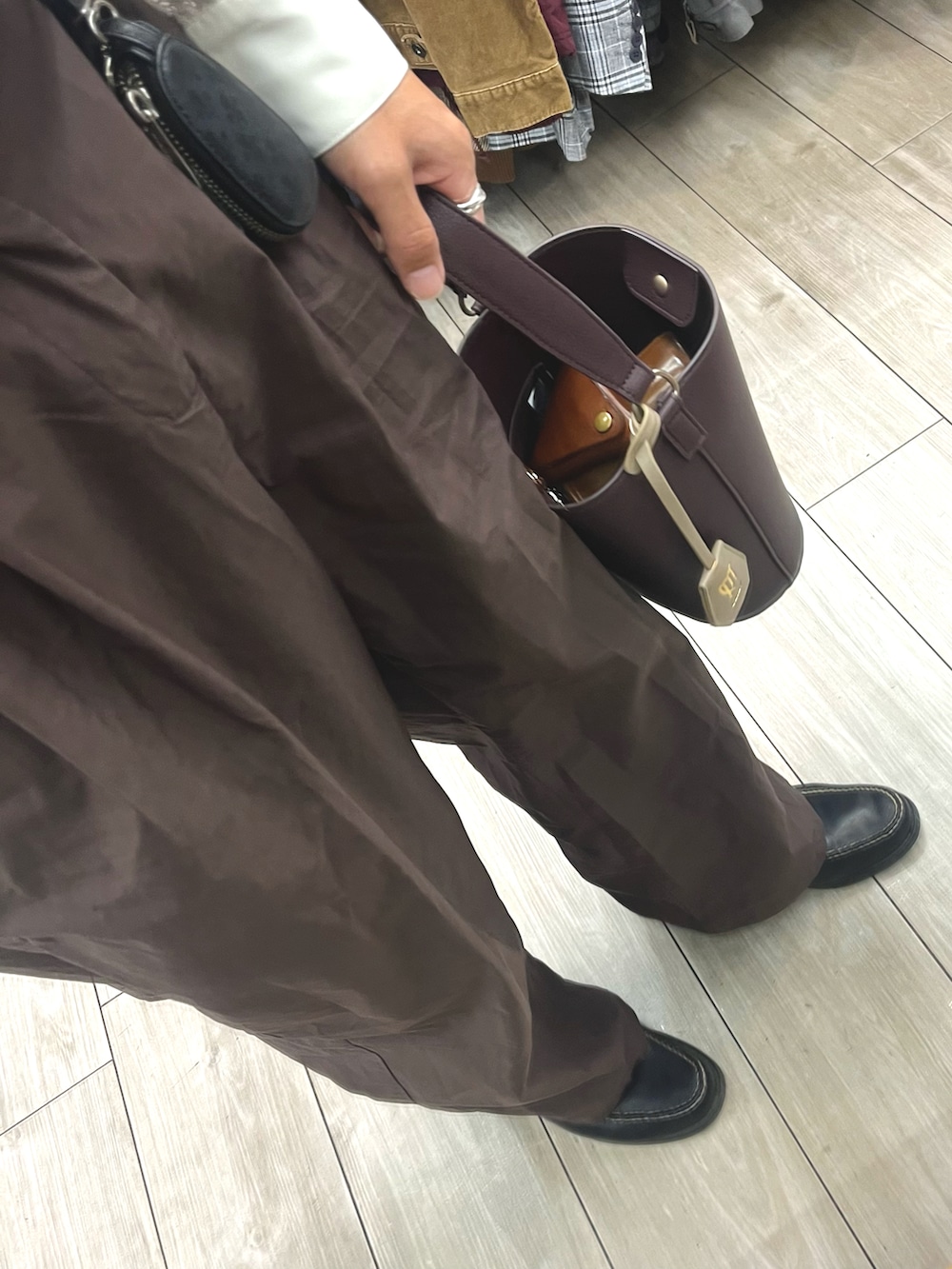 ブラック系のローファー、ブラウン系のハンドバッグ、パープル系のパンツを着用したメンズの秋コーディネートの3枚目の写真