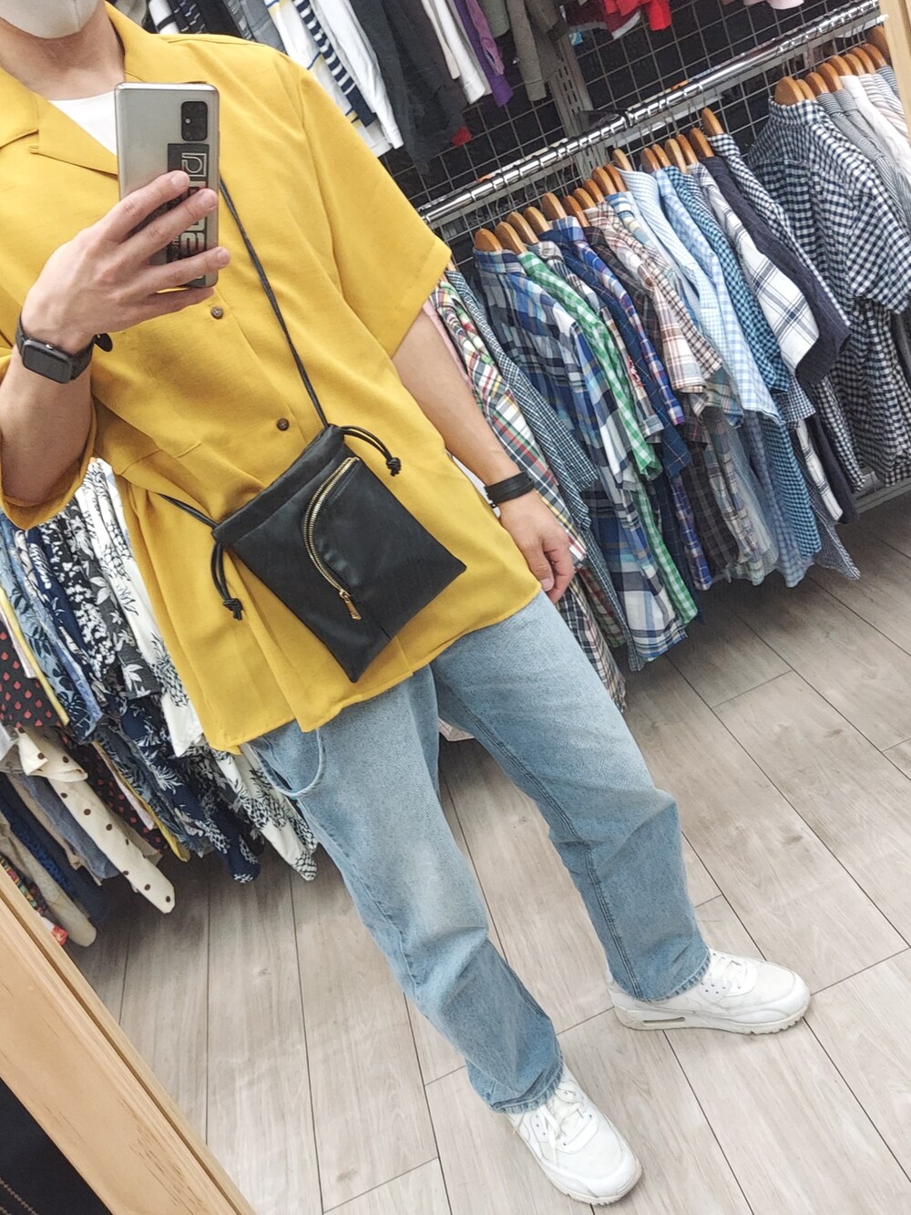 ブルー系のデニムパンツ、ホワイト系のスニーカー、ブラック系のショルダーバッグを着用したメンズの春コーディネートの2枚目の写真