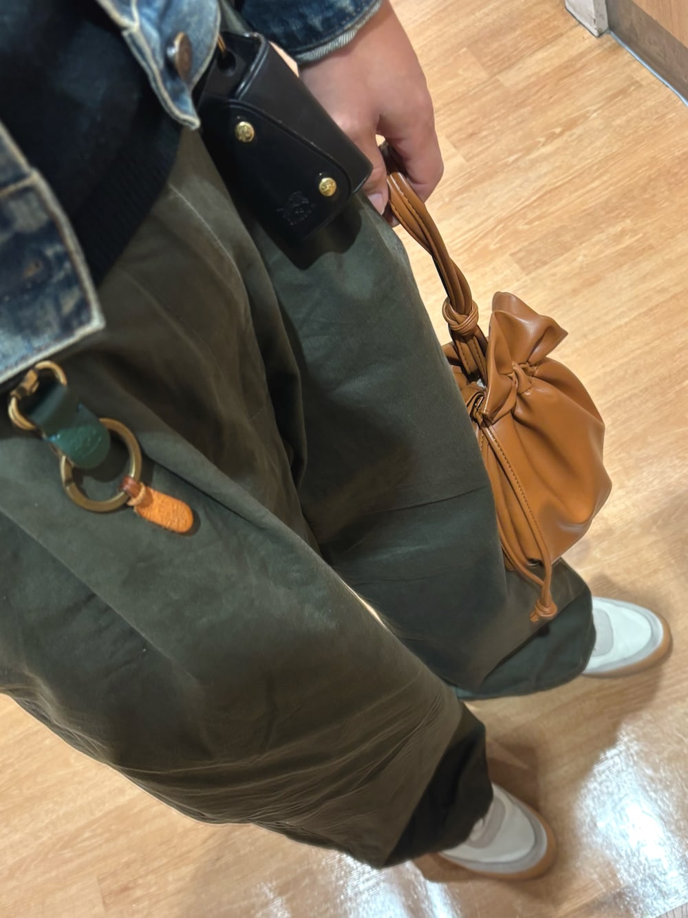 ホワイト系のスニーカー、ブラック系のニット/セーター、ブルー系のデニムジャケットを着用したメンズの秋コーディネートの3枚目の写真