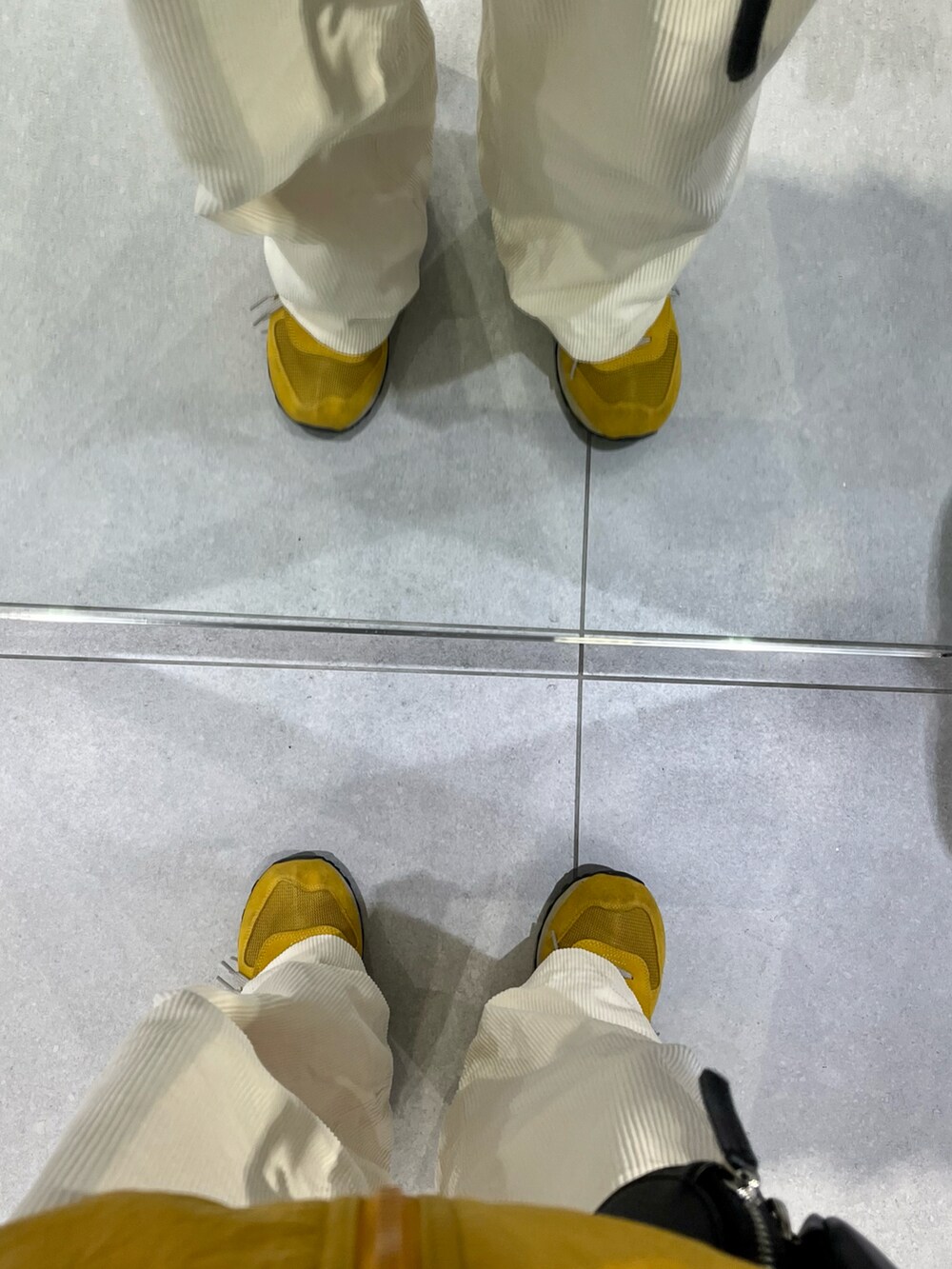 イエロー系のスニーカー、ホワイト系のパンツ、ブルー系のナイロンジャケットを着用したメンズの冬コーディネートの5枚目の写真