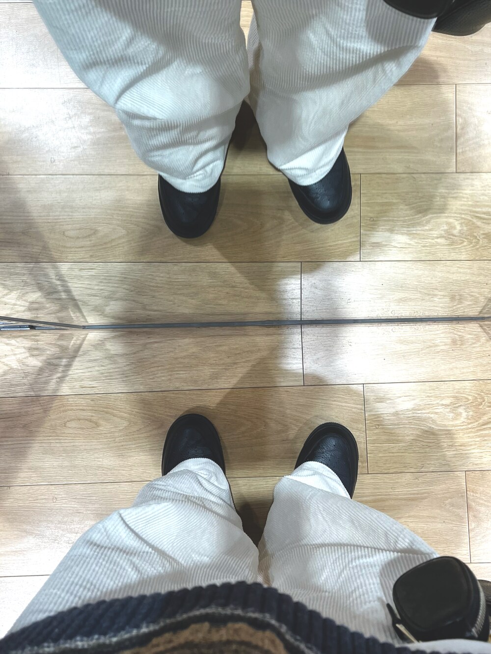 ホワイト系のパンツ、ブラック系のスニーカー、ブラック系のショルダーバッグを着用したメンズの冬コーディネートの5枚目の写真