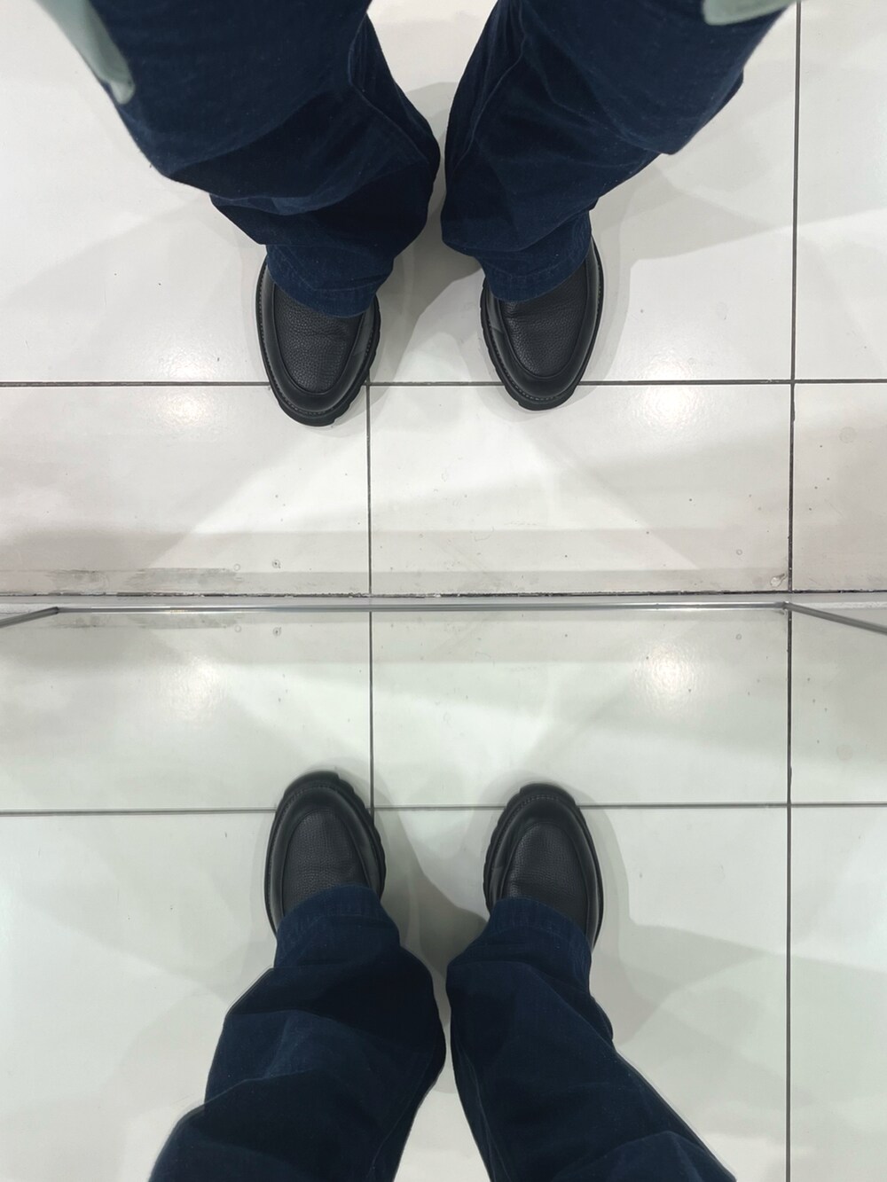 ブルー系のデニムパンツ、ブラック系のドレスシューズ、グリーン系のベストを着用したメンズの春コーディネートの5枚目の写真