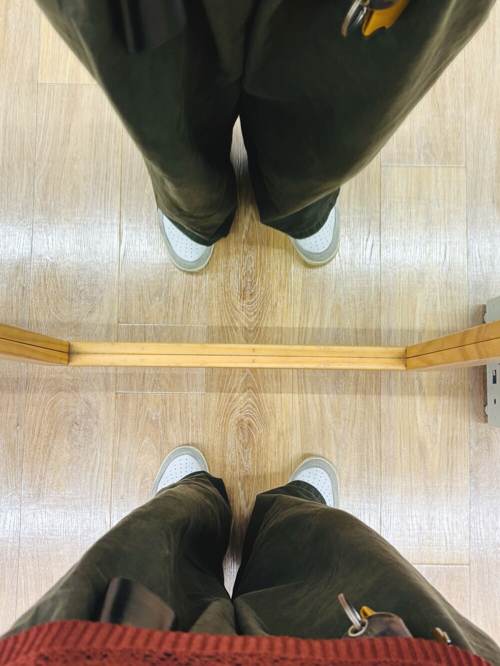 レッド系のポロシャツ、ホワイト系のスニーカー、グリーン系のパンツを着用したメンズの夏コーディネートの5枚目の写真