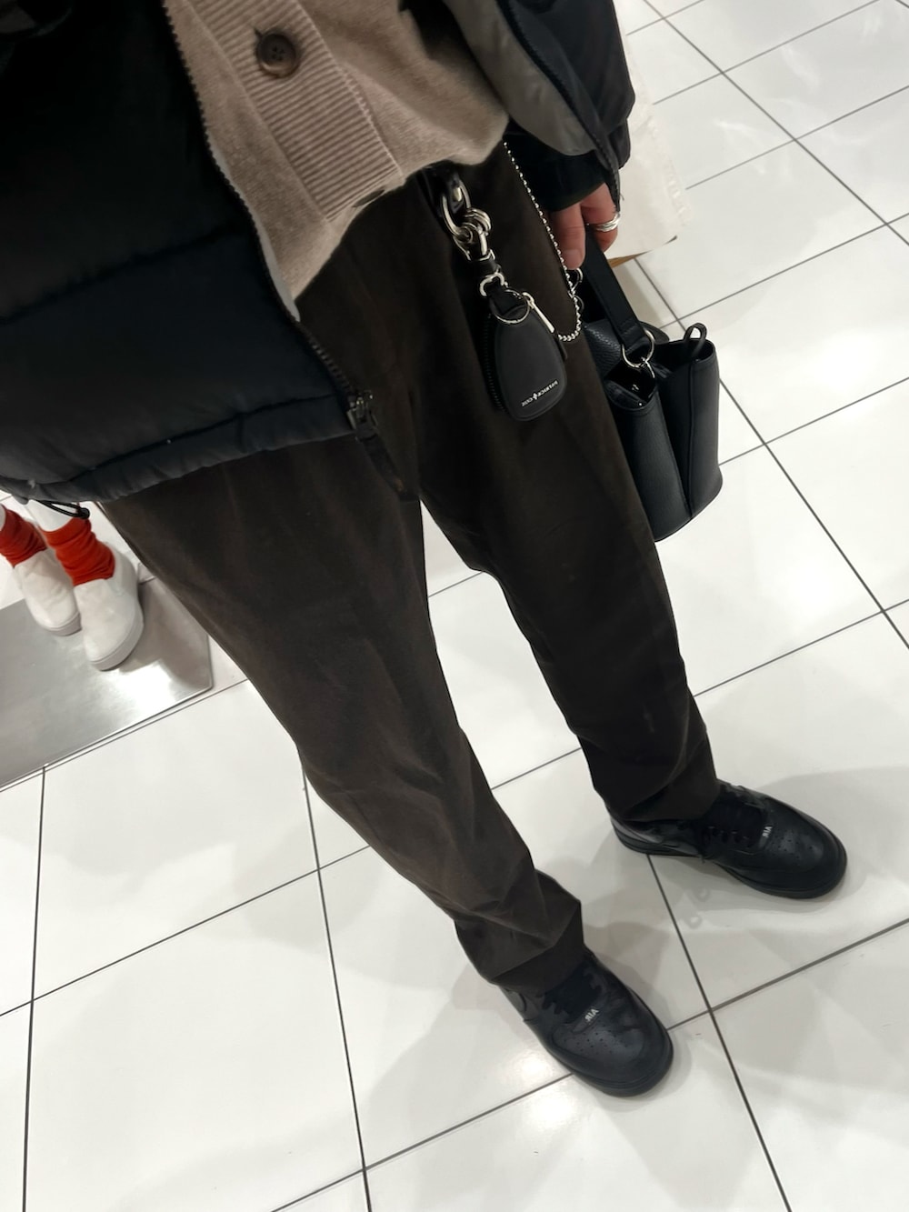 ブラウン系のパンツ、ブラック系のスニーカー、ブラック系のショルダーバッグを着用したメンズの冬コーディネートの3枚目の写真