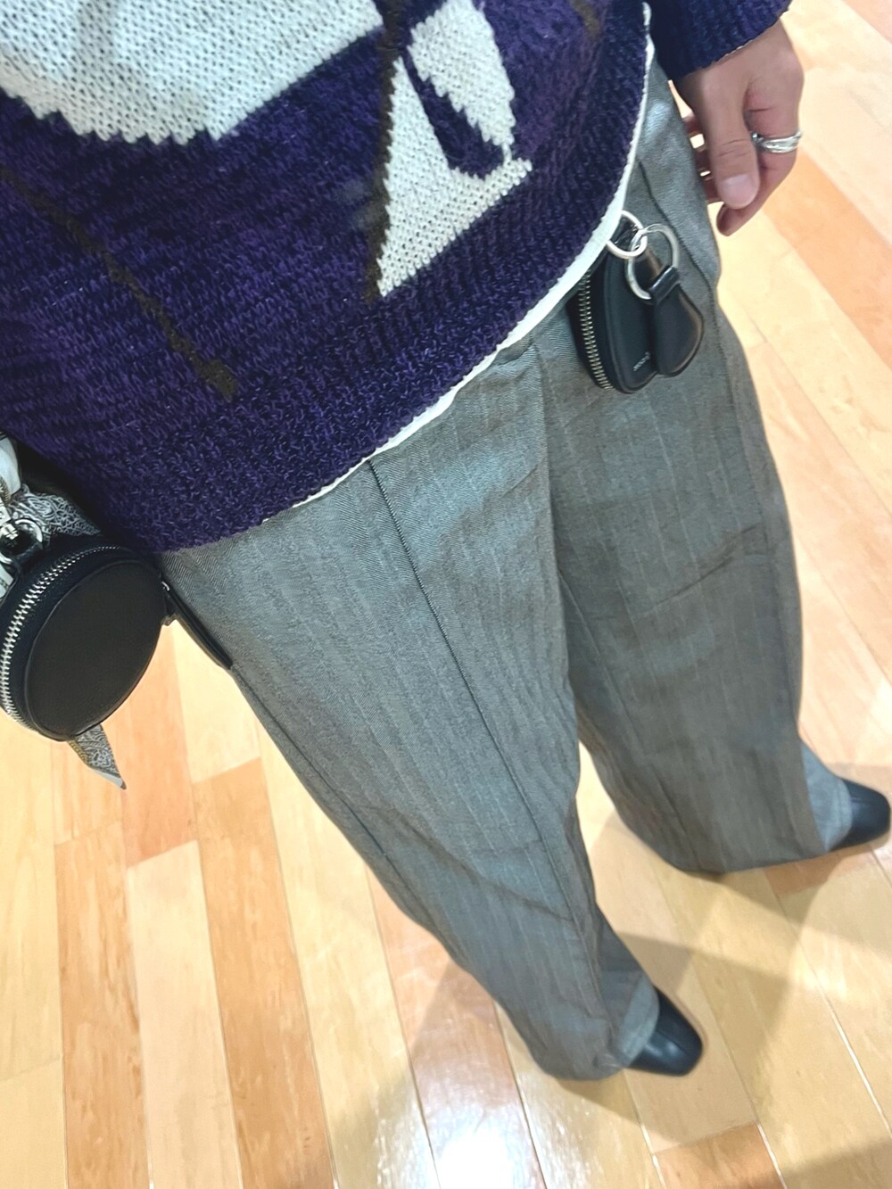 グレー系のスラックス、ブラック系のショルダーバッグ、パープル系のニット/セーターを着用したメンズの冬コーディネートの3枚目の写真