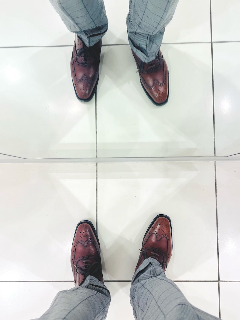 ブラウン系のドレスシューズ、グレー系のスラックス、ブラウン系のトートバッグを着用したメンズの春コーディネートの5枚目の写真