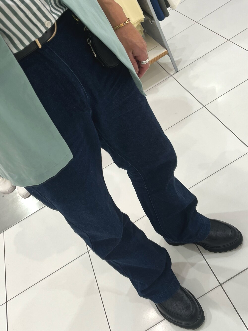 ブルー系のデニムパンツ、ブラック系のドレスシューズ、グリーン系のベストを着用したメンズの春コーディネートの3枚目の写真