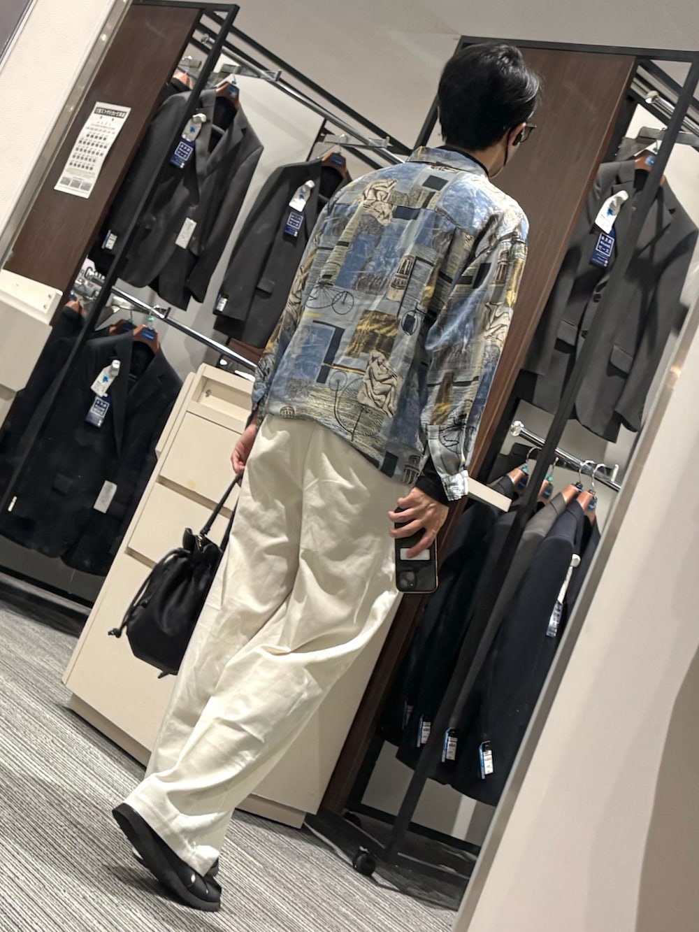 ホワイト系のスラックス、ブラック系のTシャツ/カットソー、ブラック系のサンダルを着用したメンズの夏コーディネートの2枚目の写真
