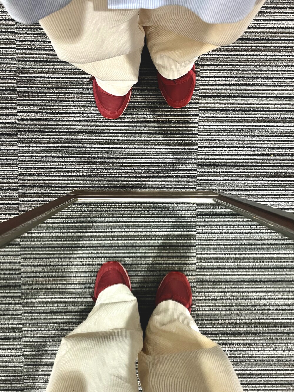 レッド系のスニーカー、ホワイト系のパンツ、ベージュ系のショルダーバッグを着用したメンズの春コーディネートの5枚目の写真