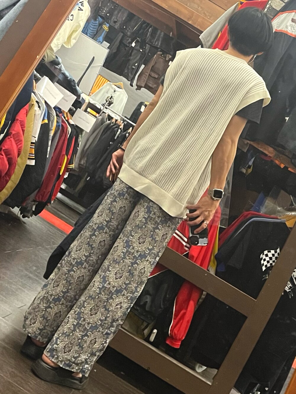ブラック系のサンダル、ブルー系のパンツ、ベージュ系のベストを着用したメンズの秋コーディネートの2枚目の写真