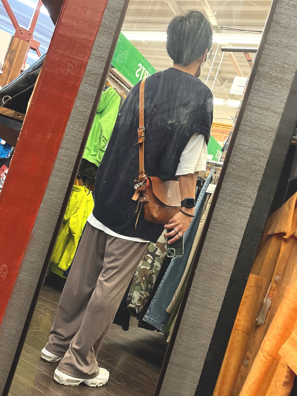 ホワイト系のスニーカー、ブラウン系のパンツ、ブルー系のベストを着用したメンズの秋コーディネートの2枚目の写真