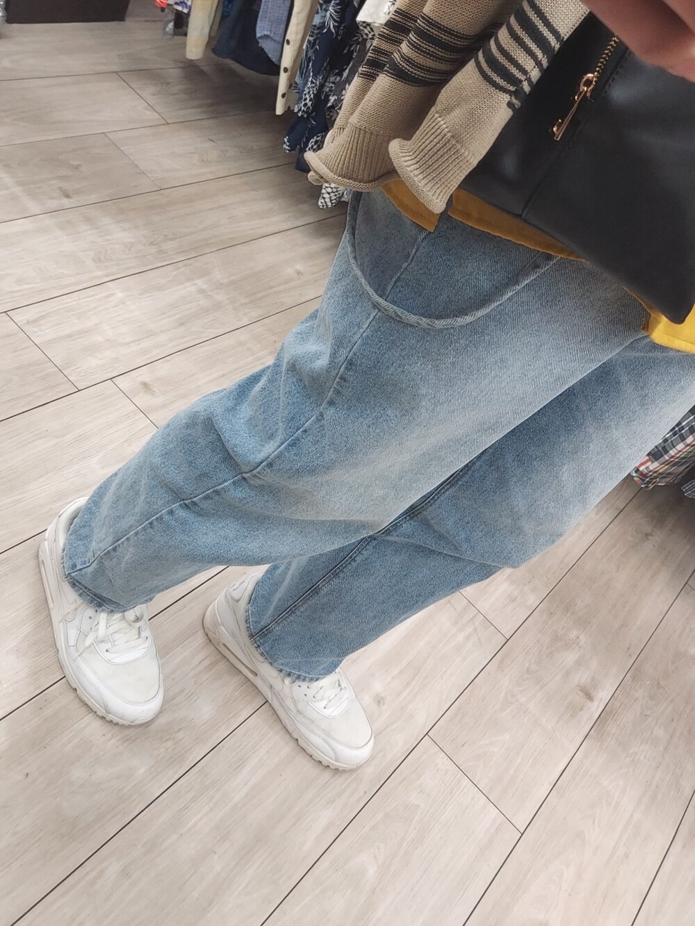 ブルー系のデニムパンツ、ホワイト系のスニーカー、ブラック系のショルダーバッグを着用したメンズの春コーディネートの5枚目の写真