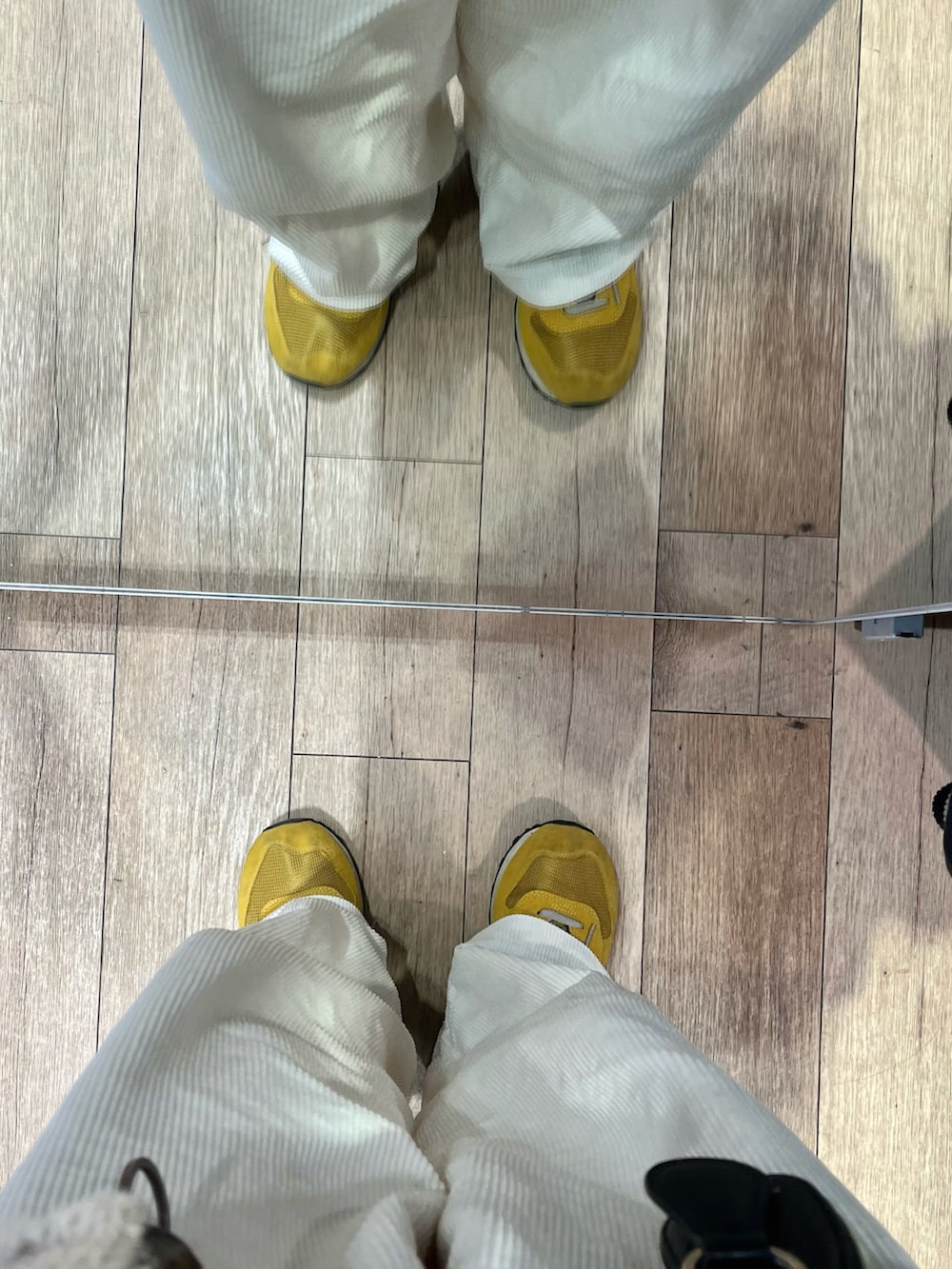 ホワイト系のパンツ、イエロー系のスニーカー、ブラック系のショルダーバッグを着用したメンズの冬コーディネートの5枚目の写真