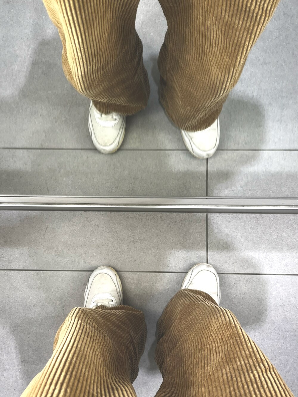 ブラウン系のパンツ、ホワイト系のスニーカー、ブラウン系のボディバッグ/ウエストポーチを着用したメンズの冬コーディネートの5枚目の写真
