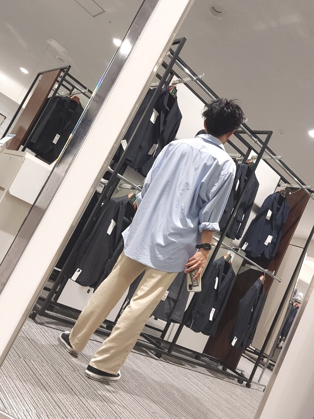 ブラック系のスニーカー、ベージュ系のパンツ、ホワイト系のタンクトップを着用したメンズの秋コーディネートの2枚目の写真