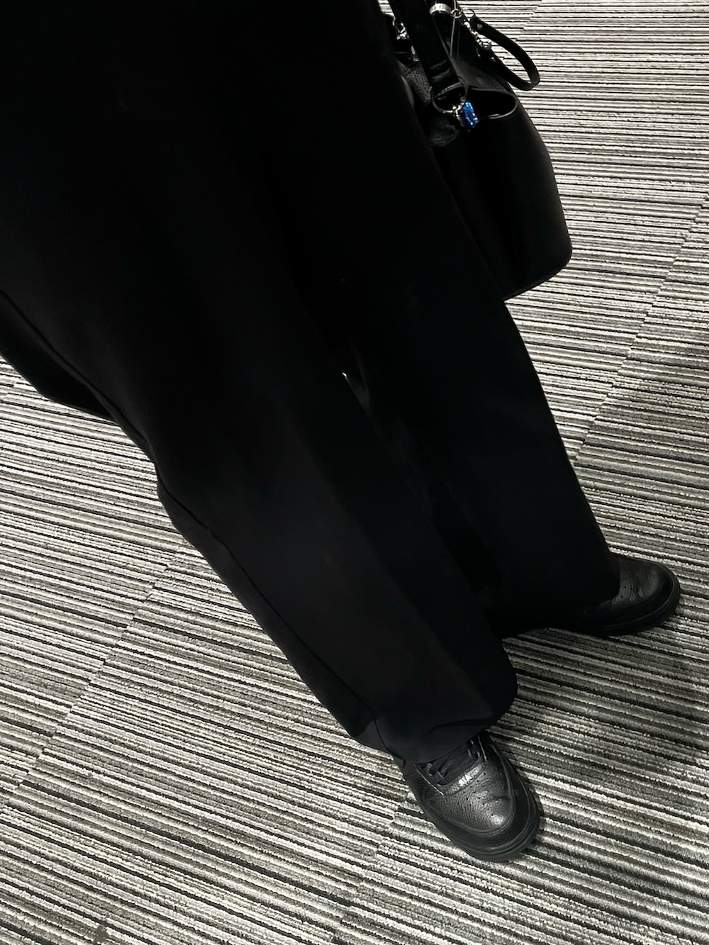 ブラック系のスニーカー、ブラック系のパンツ、ブラック系のショルダーバッグを着用したメンズの冬コーディネートの3枚目の写真