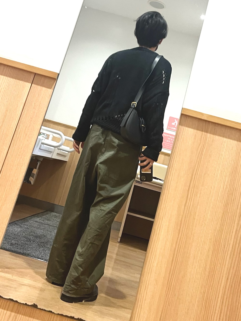 グリーン系のパンツ、ブラック系のドレスシューズ、ブラック系のニット/セーターを着用したメンズの春コーディネートの2枚目の写真