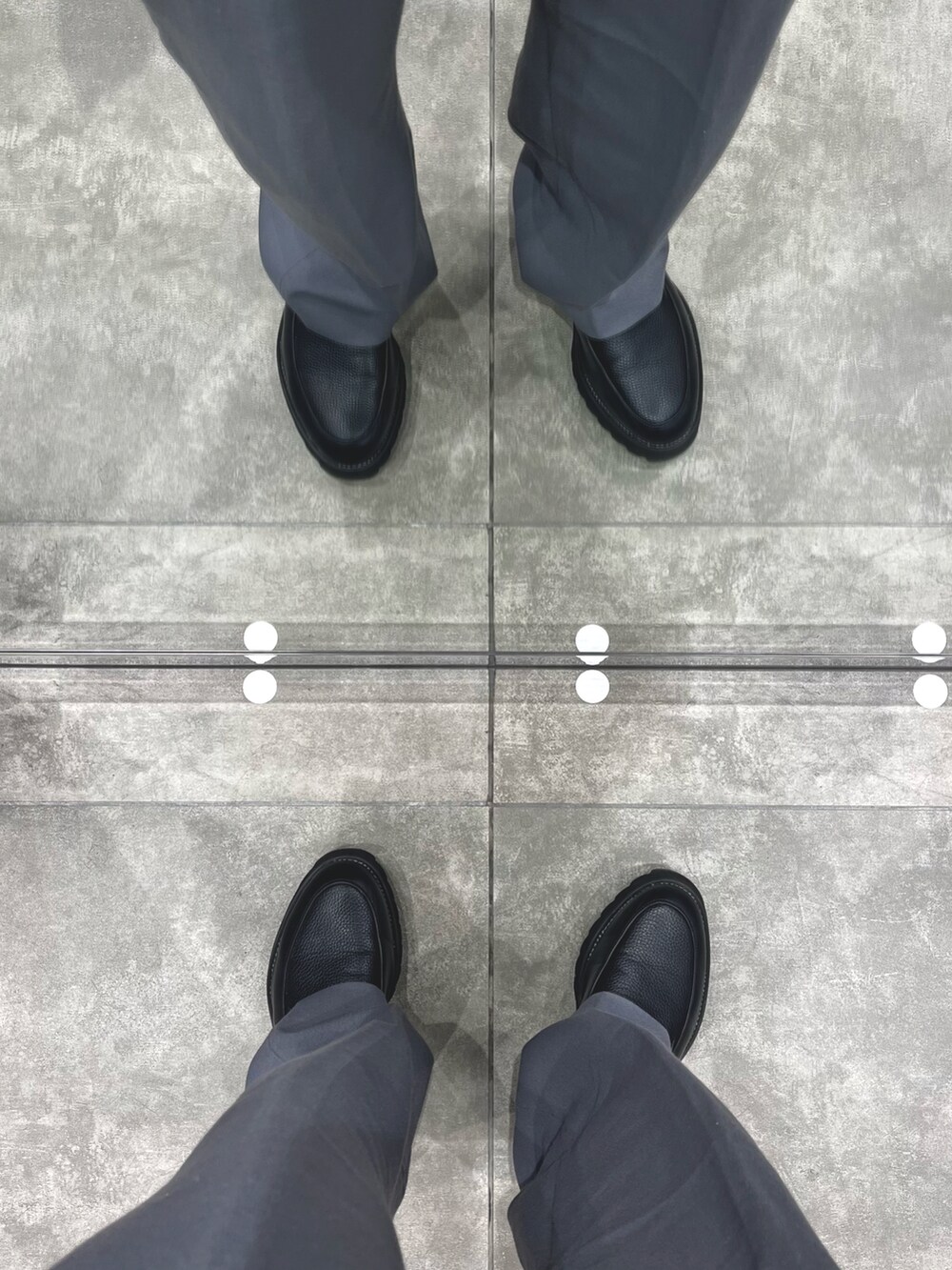 グレー系のパンツ、ブラック系のドレスシューズ、ブラック系のライダースジャケットを着用したメンズの春コーディネートの5枚目の写真