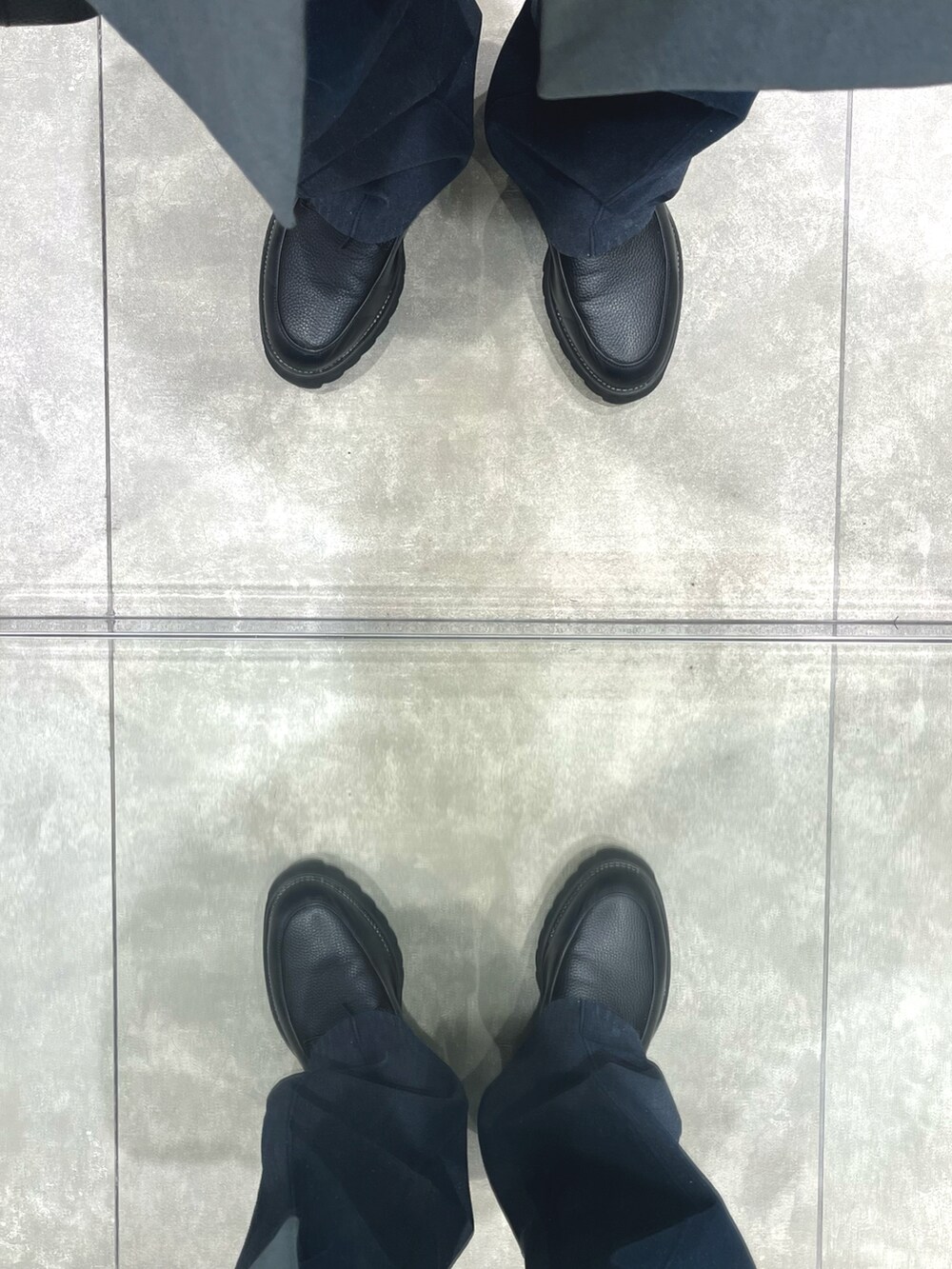 ブラック系のショルダーバッグ、ブラック系のドレスシューズ、ブルー系のデニムパンツを着用したメンズの春コーディネートの5枚目の写真