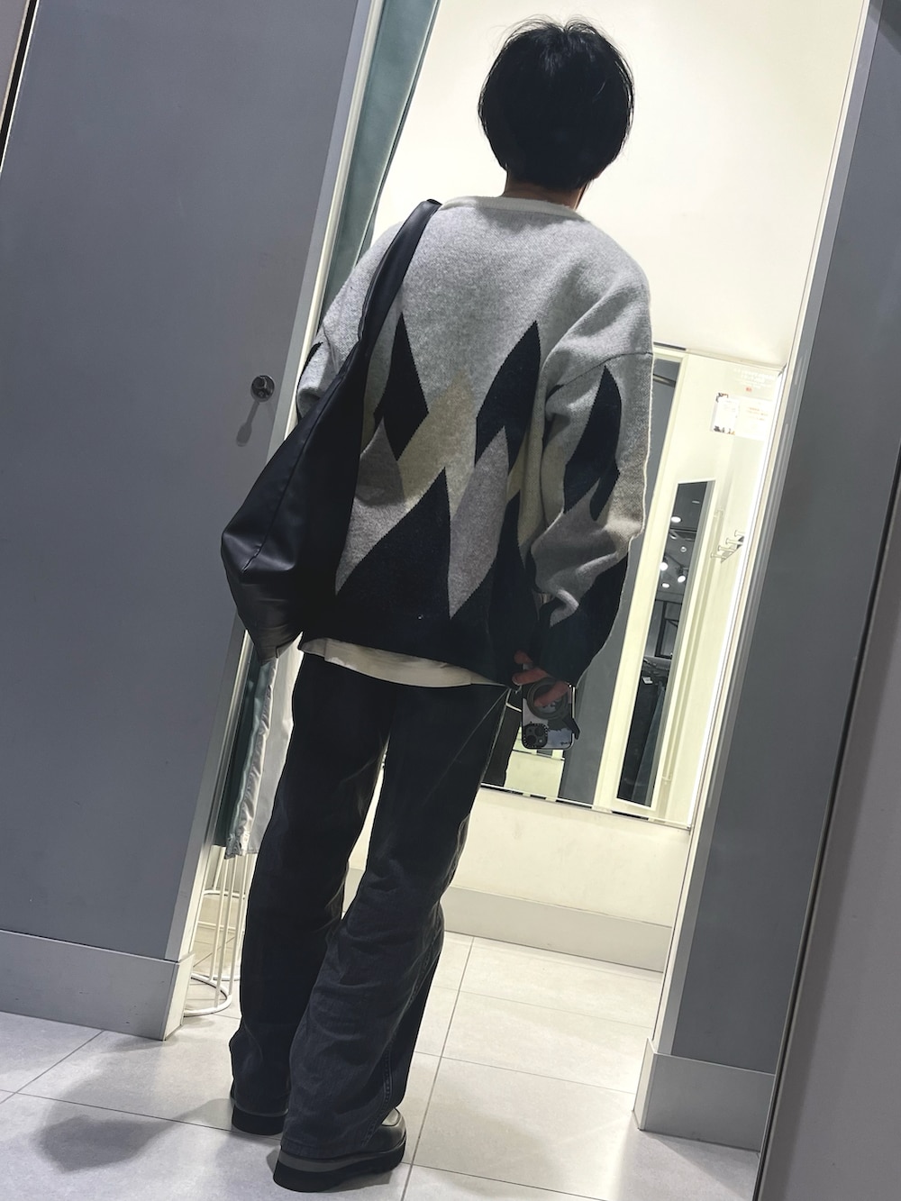 ブラック系のパンツ、ブラック系のドレスシューズ、ホワイト系のニット/セーターを着用したメンズの冬コーディネートの2枚目の写真