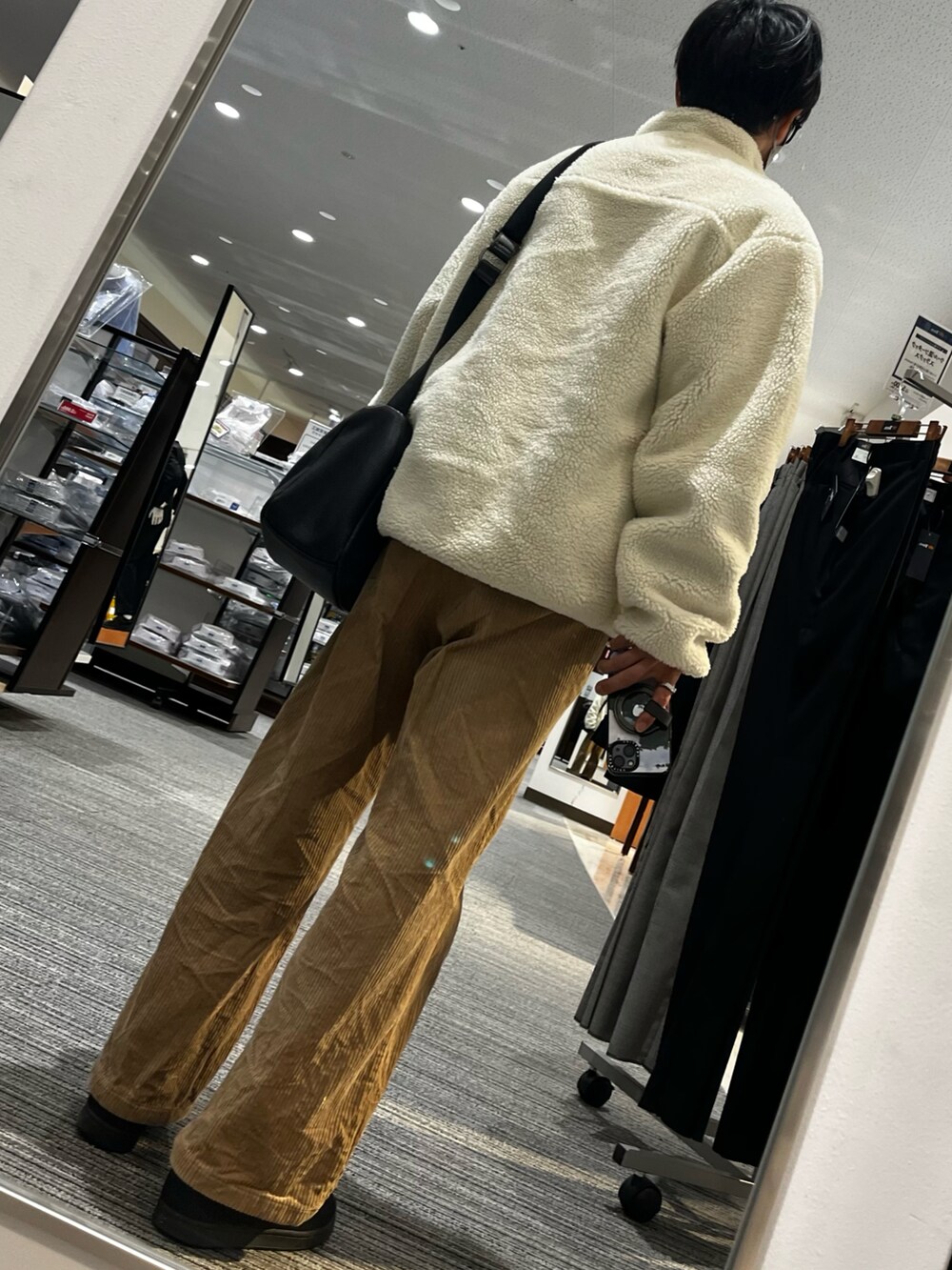 ブラウン系のパンツ、ブラック系のスニーカー、ブラック系のショルダーバッグを着用したメンズの春コーディネートの2枚目の写真