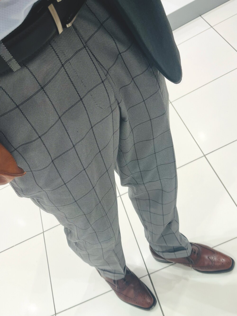 ブラウン系のドレスシューズ、グレー系のスラックス、ブラウン系のトートバッグを着用したメンズの春コーディネートの3枚目の写真