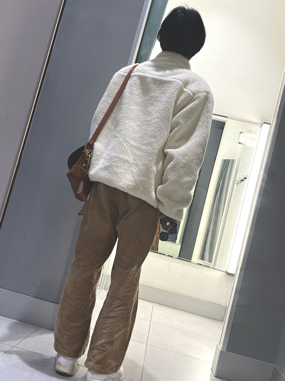 ブラウン系のパンツ、ホワイト系のスニーカー、ブラウン系のボディバッグ/ウエストポーチを着用したメンズの冬コーディネートの2枚目の写真