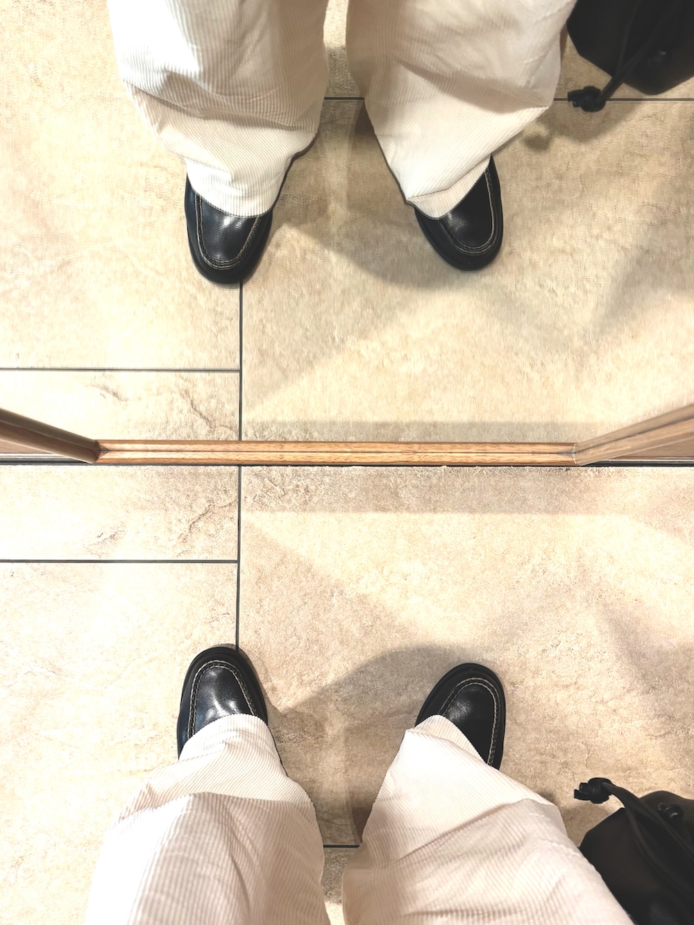 ブラック系のブルゾン、ホワイト系のパンツ、ブラック系のローファーを着用したメンズの春コーディネートの5枚目の写真