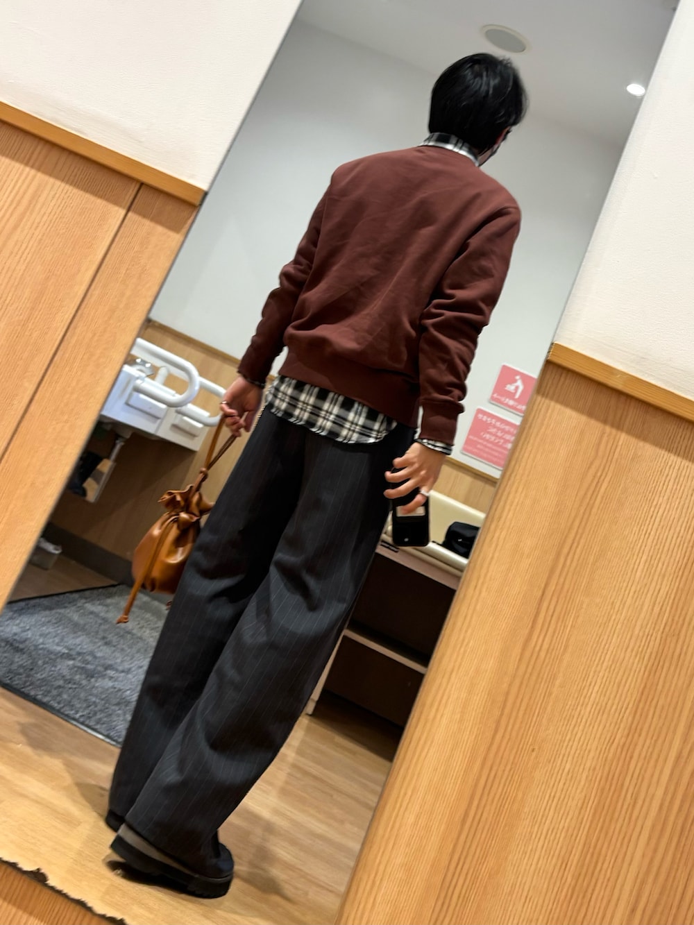 ブラウン系のスウェット、ブラウン系のショルダーバッグ、ブラック系のドレスシューズを着用したメンズの冬コーディネートの2枚目の写真