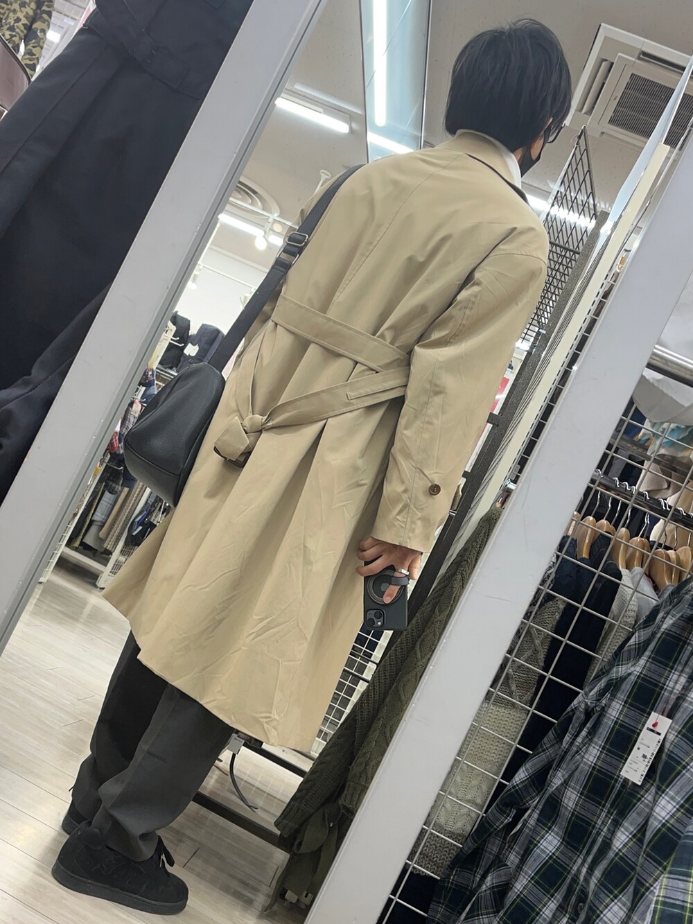 ブラック系のスニーカー、ベージュ系のトレンチコート、ブラック系のショルダーバッグを着用したメンズの冬コーディネートの2枚目の写真