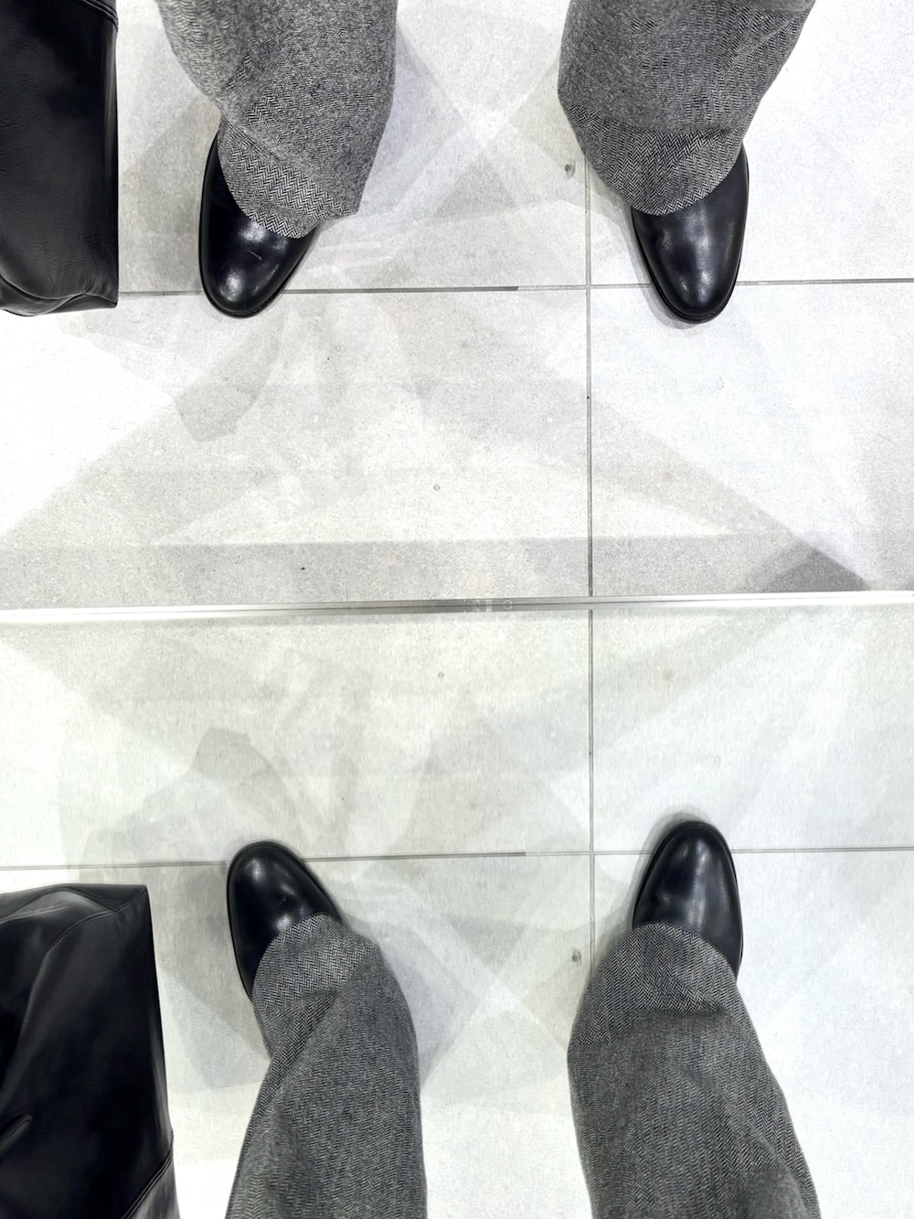 ブラック系のブーツ、ブラック系のジャケット/アウター、グレー系のスラックスを着用したメンズの冬コーディネートの5枚目の写真