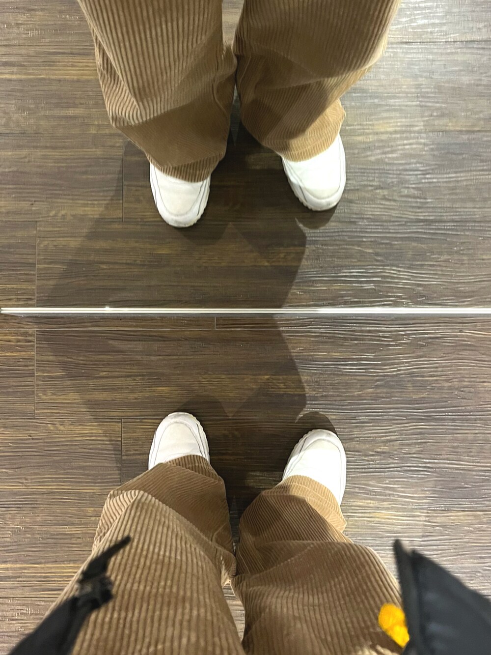 ブラウン系のパンツ、ホワイト系のスニーカー、ブラウン系のボディバッグ/ウエストポーチを着用したメンズの冬コーディネートの5枚目の写真