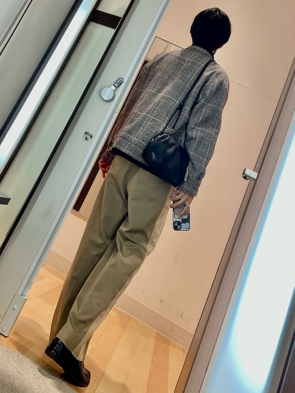 ベージュ系のパンツ、ブラック系のローファー、ブラック系のショルダーバッグを着用したメンズの冬コーディネートの2枚目の写真