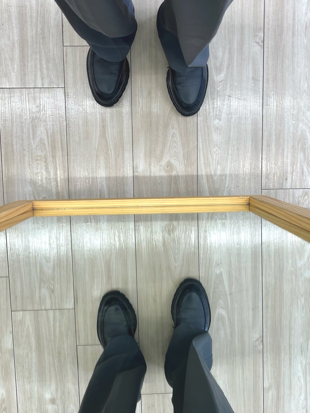 グレー系のスラックス、ブラック系のドレスシューズ、ブラック系のショルダーバッグを着用したメンズの秋コーディネートの5枚目の写真