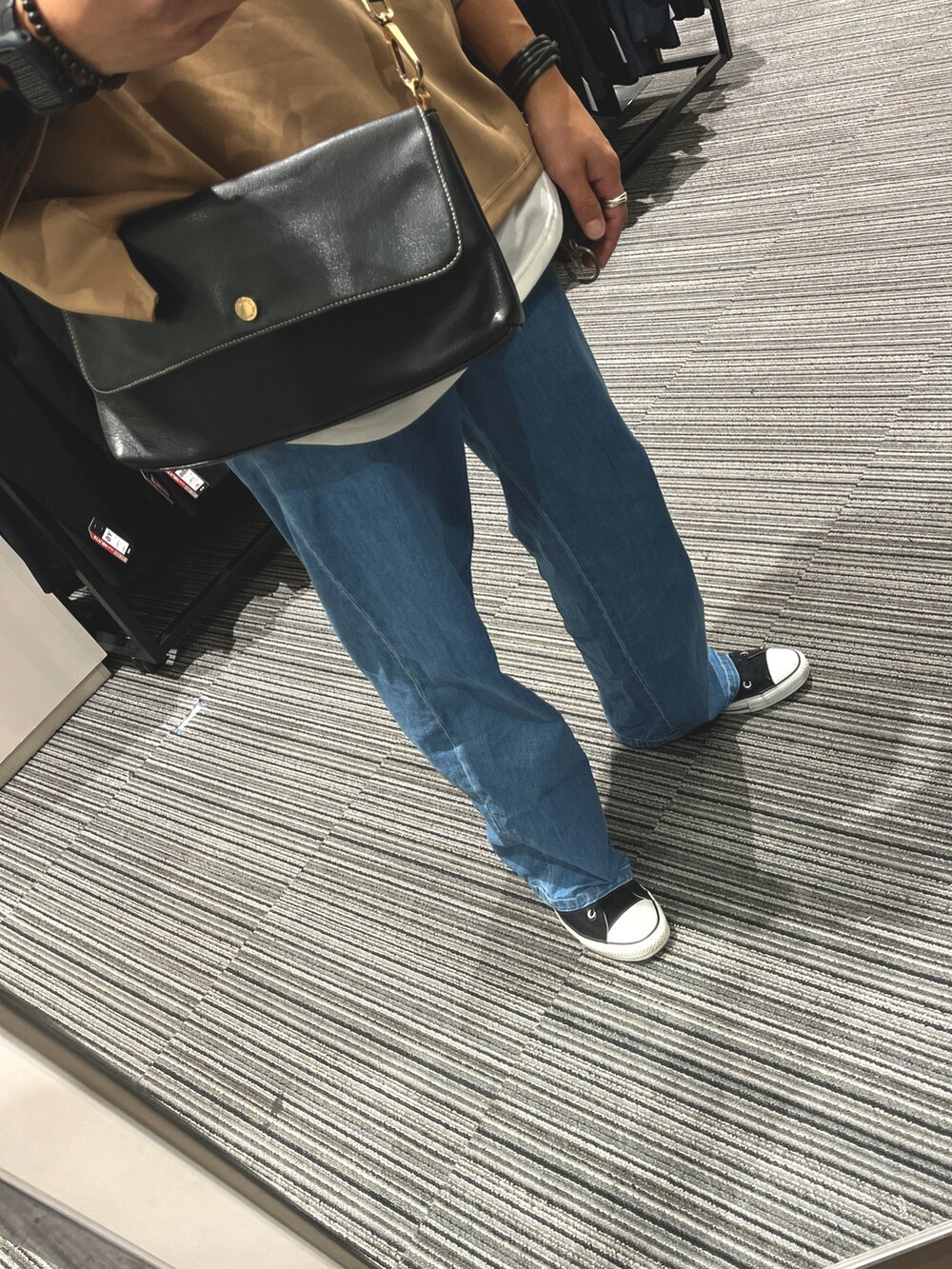 ブラック系のスニーカー、ブラック系のバッグ、ブルー系のデニムパンツを着用したメンズの秋コーディネートの3枚目の写真