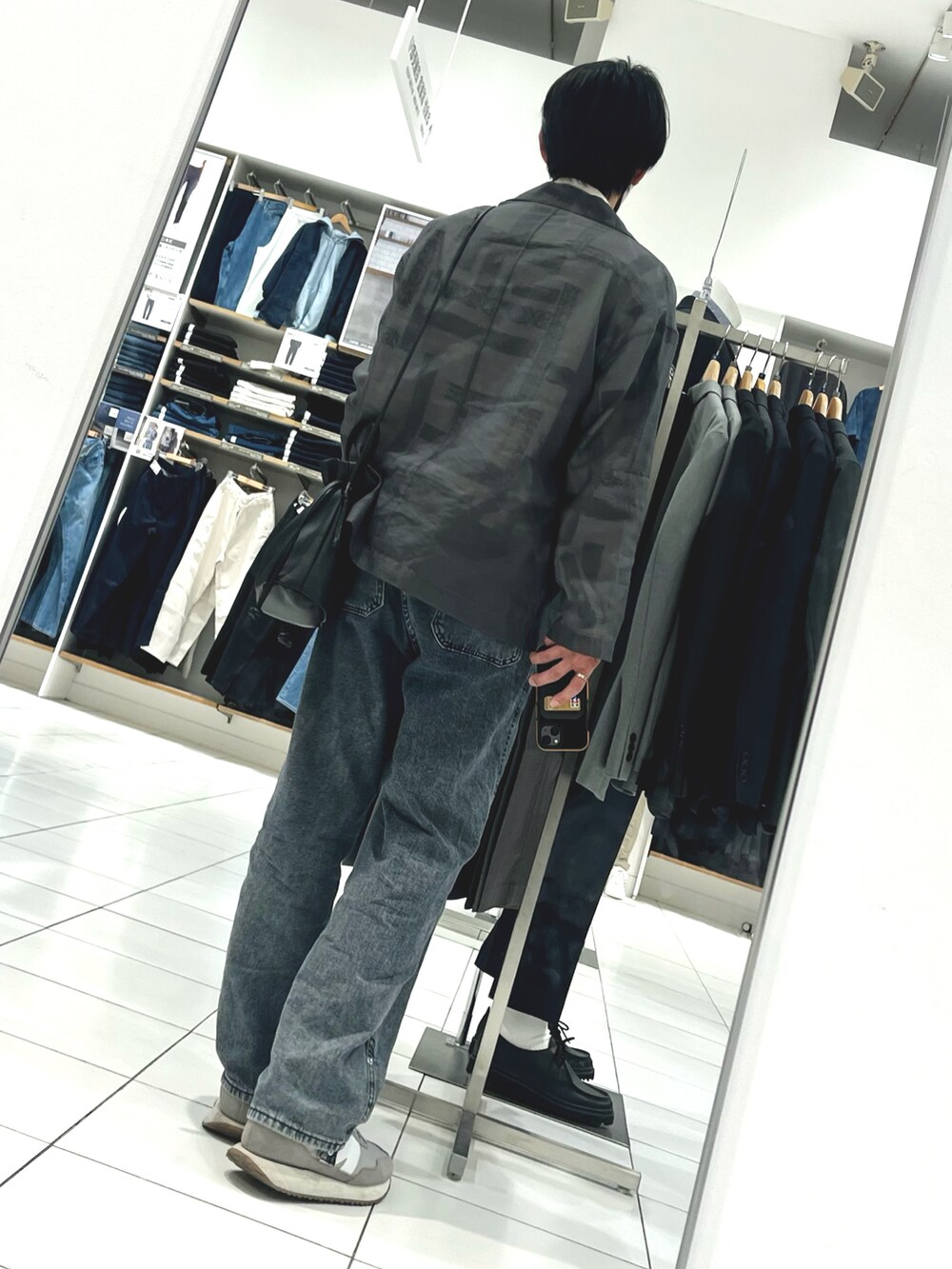 グレー系のデニムパンツ、グレー系のスニーカー、ブラック系のショルダーバッグを着用したメンズの春コーディネートの2枚目の写真