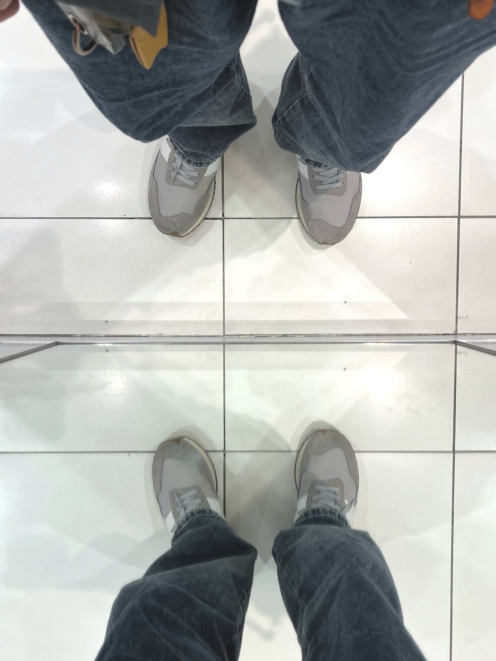 グレー系のデニムパンツ、グレー系のスニーカー、ブラック系のショルダーバッグを着用したメンズの春コーディネートの5枚目の写真