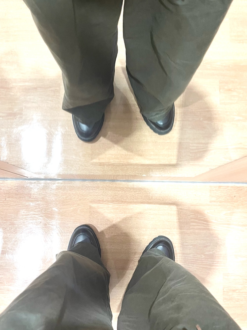 グリーン系のパンツ、ブラック系のドレスシューズ、ブラック系のニット/セーターを着用したメンズの春コーディネートの5枚目の写真