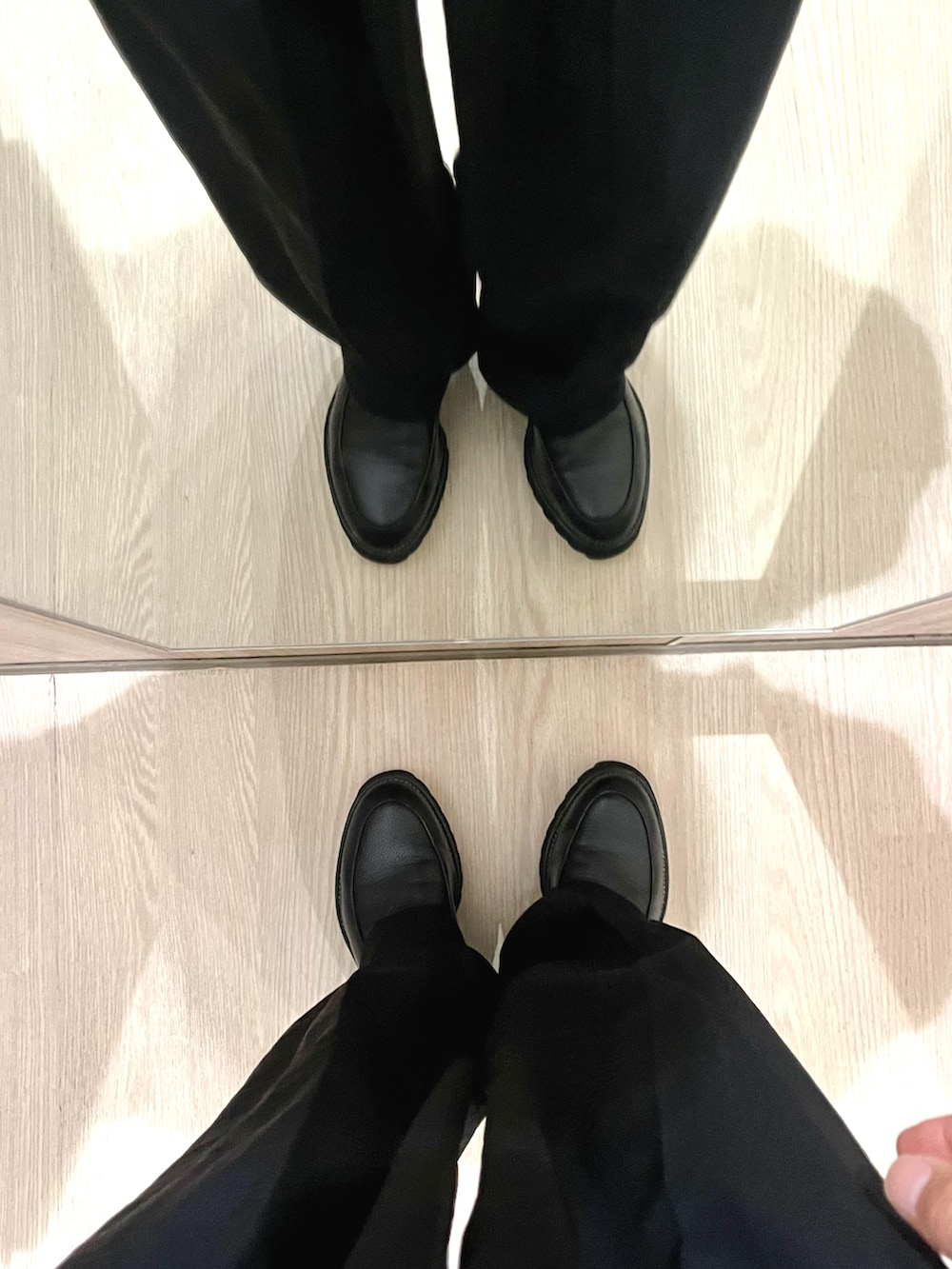 ブラック系のドレスシューズ、ブラック系のスラックス、ホワイト系のニット/セーターを着用したメンズの冬コーディネートの5枚目の写真